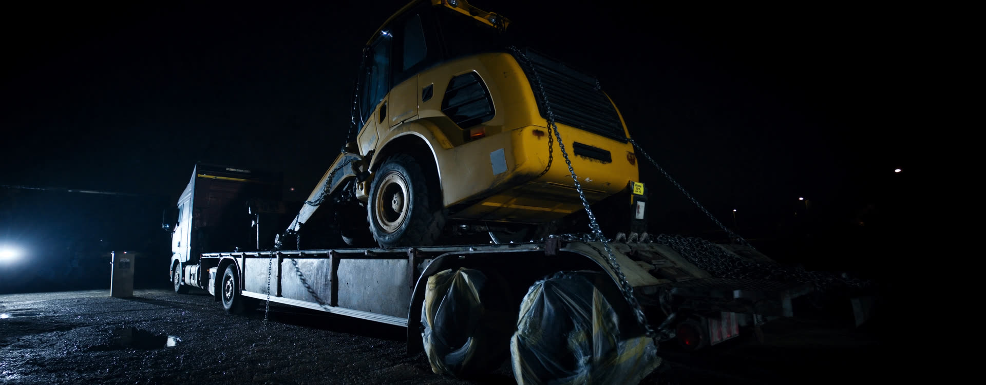 An oversized load secured on a flatbed under yard lighting