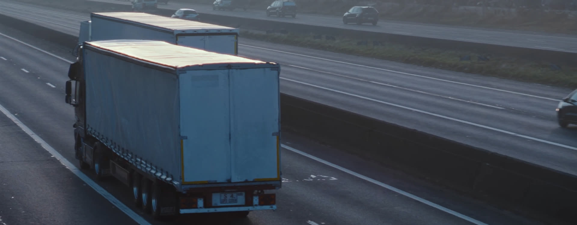 A curtain-side trailer on a motorway at first light